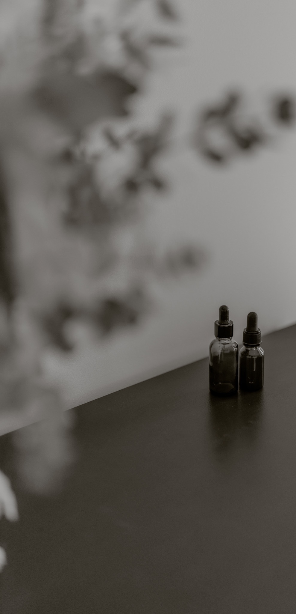 Homeopathic remedy bottles on a desk among a flower arrangement in the homeopathic clinic office for Nikki Hermens, Homeopath, in Latrobe Valley Gippsland